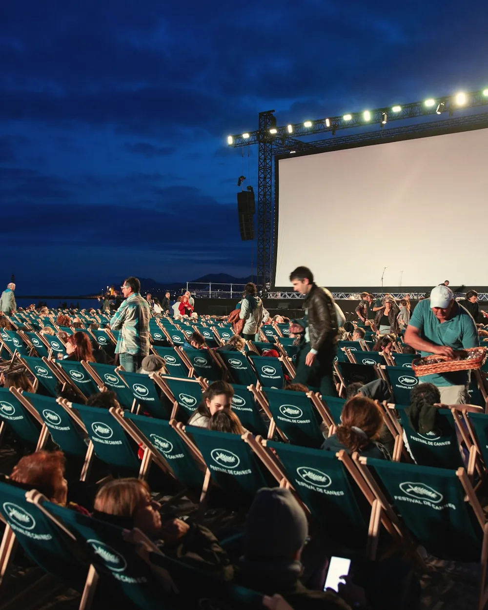 An open-air cinema filling up at blue hour